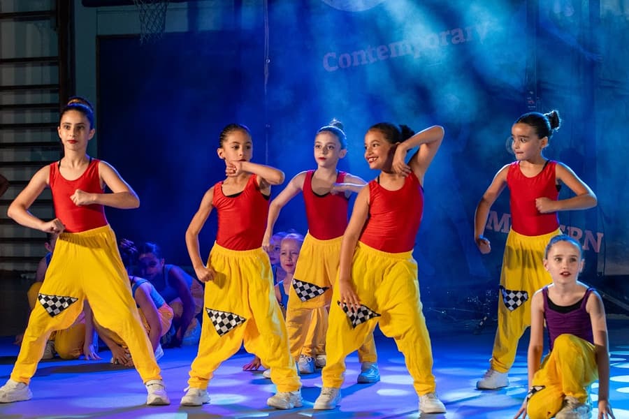 רקדניות צעירות במכנסי הרמון צהובים עם אגרופים מורמים